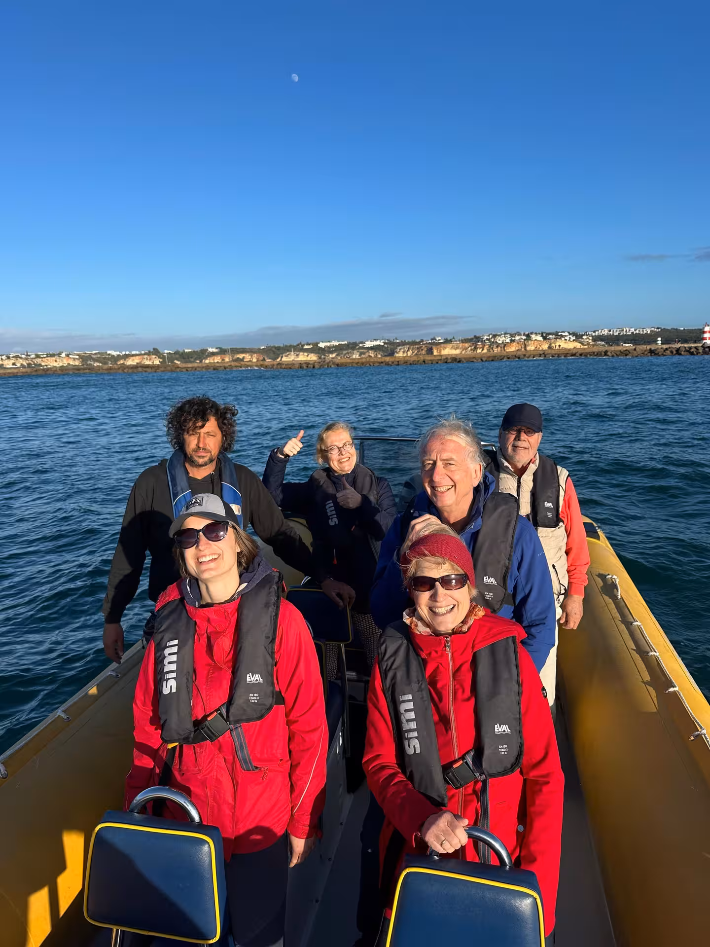 Happy tourists in life jackets aboard a yellow RIB boat on Benagil cave tour departing Portimao Algarve coast