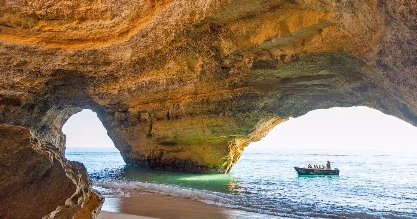 Boat tour entering Benagil Cave at golden hour, showcasing Algarve sea arches, hidden beach and turquoise Atlantic water