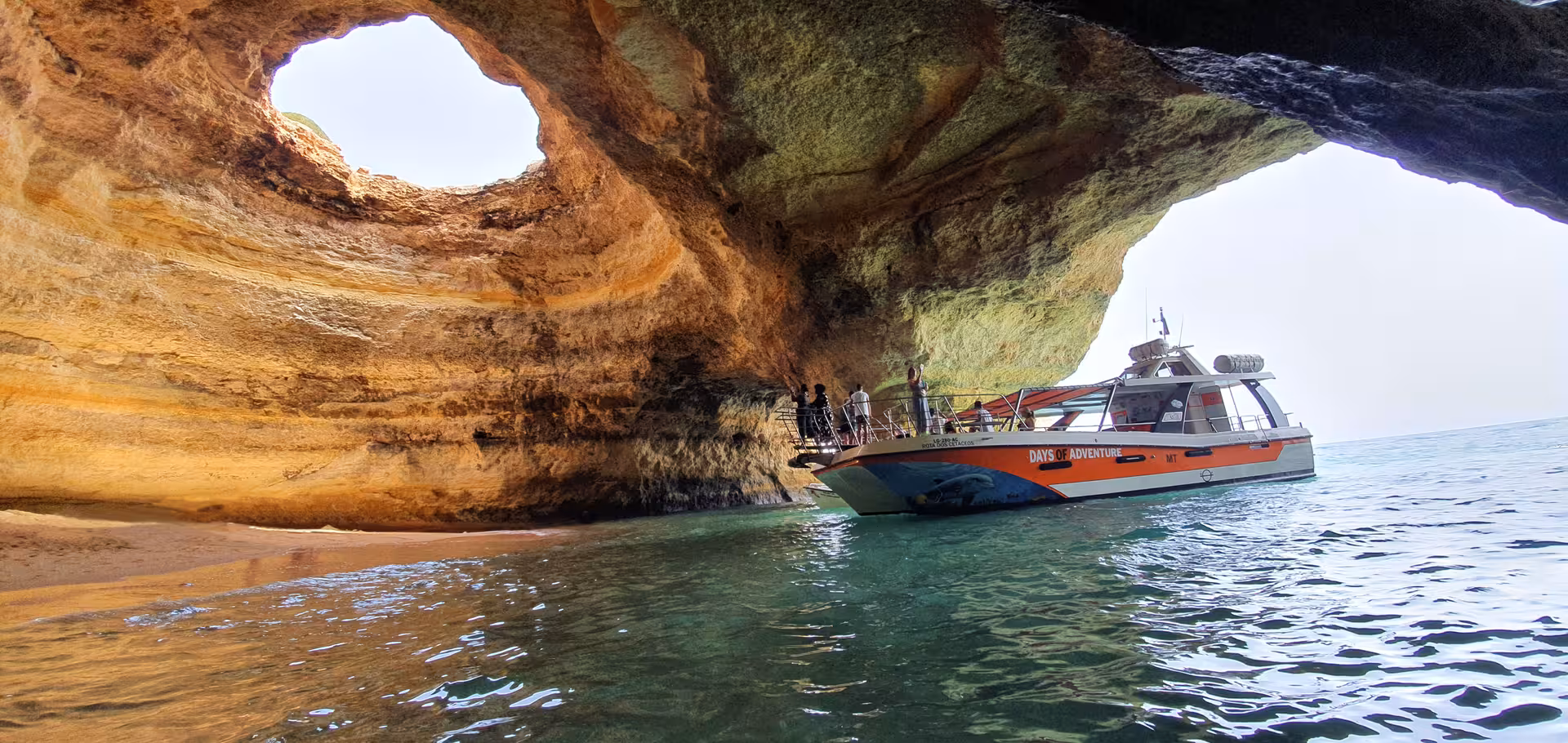 Catamaran entering the iconic Benagil Cave with its famous skylight opening on an Algarve boat tour from Lagos Portugal