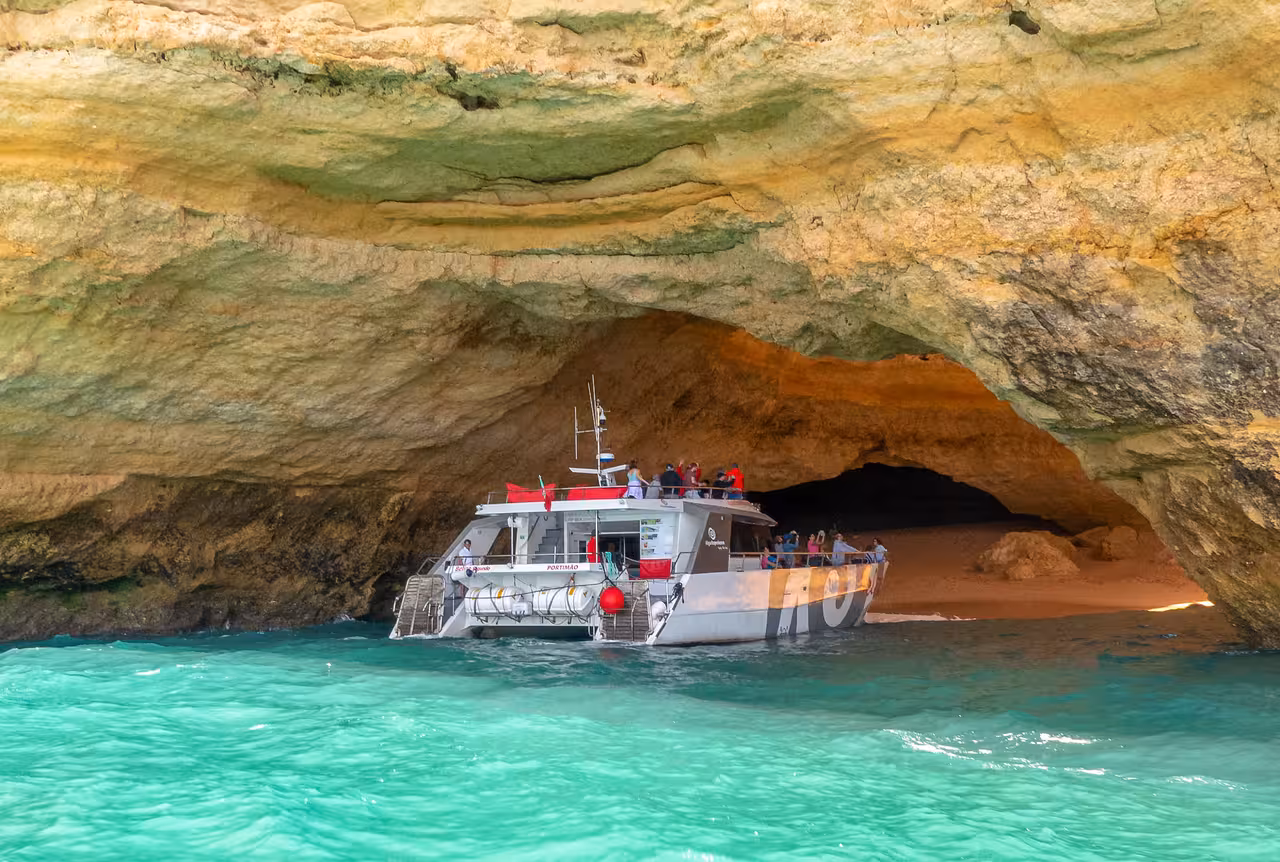 Portimao catamaran cruise entering stunning Benagil sea cave with turquoise waters and golden sandstone arch in Algarve