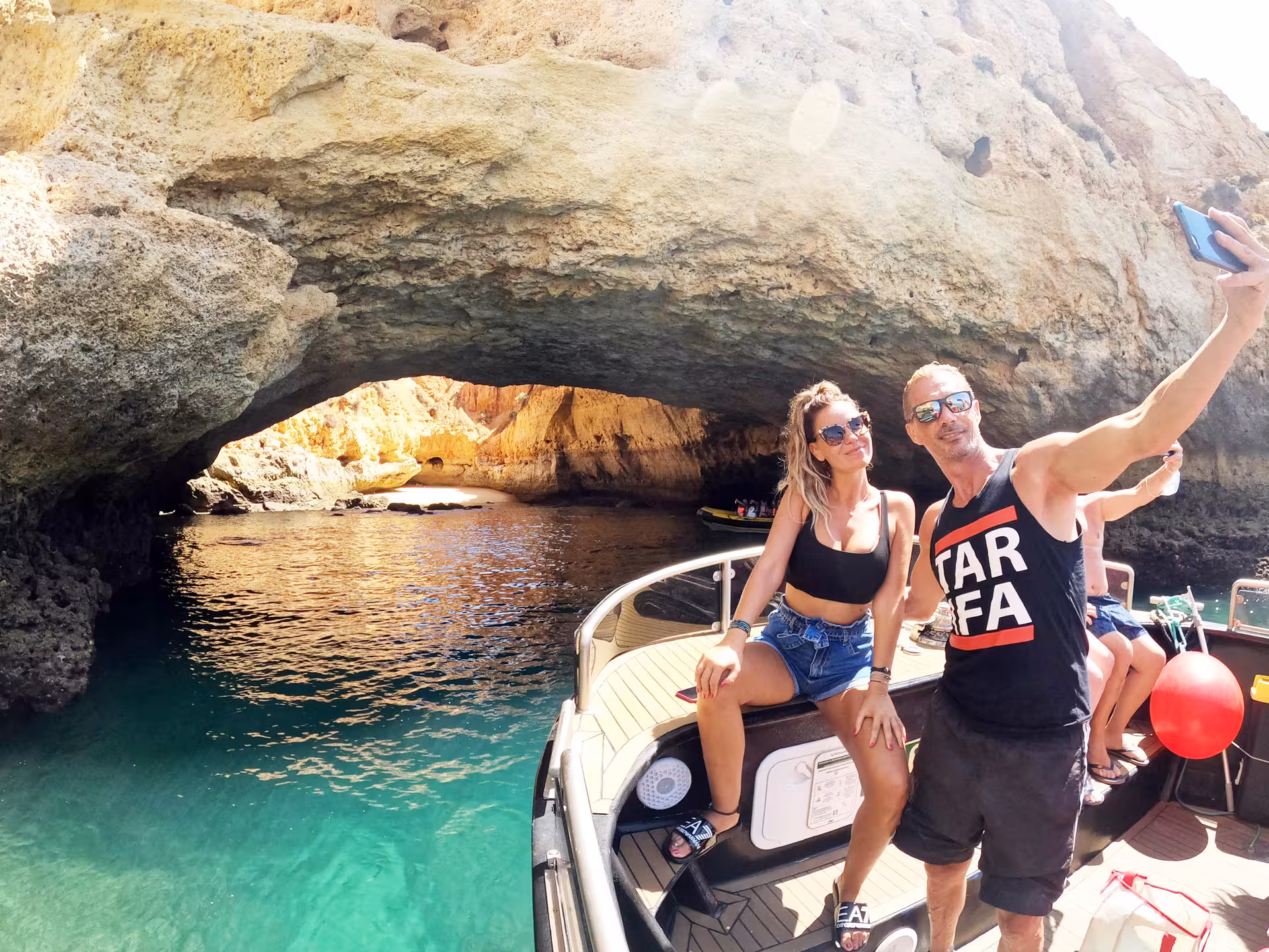 Couple taking a selfie on a boat inside stunning Benagil sea cave during Algarve coast tour from Portimao