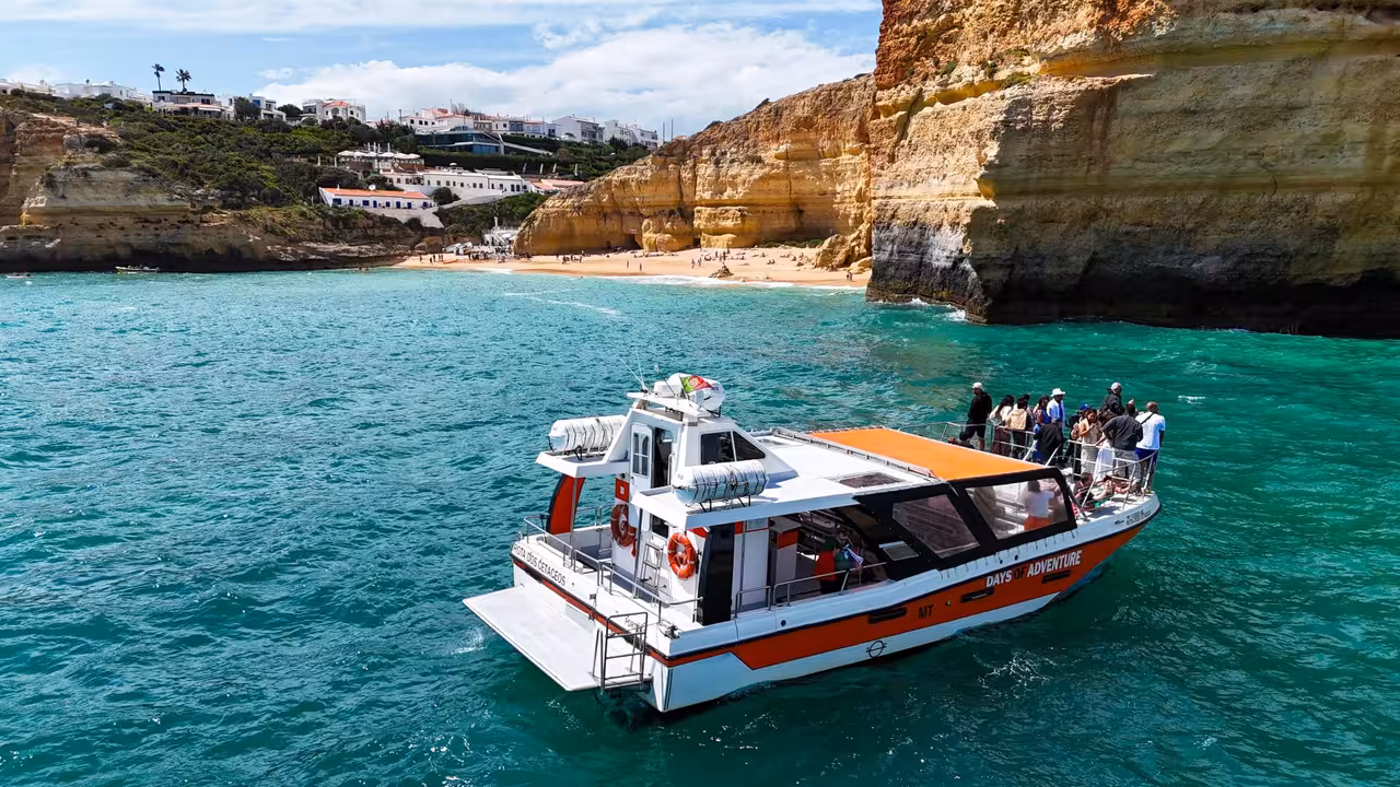 Days of Adventure tour boat with guests exploring the scenic Algarve coastline near Benagil Cave from Lagos