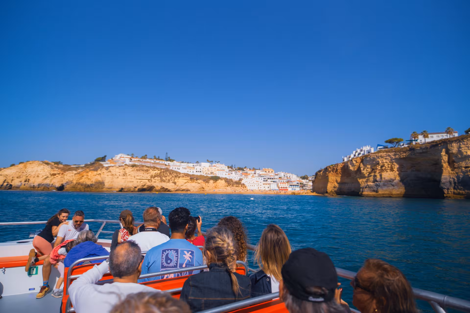 Excited guests enjoying a scenic Algarve coastline boat tour near Benagil Cave with clear blue skies