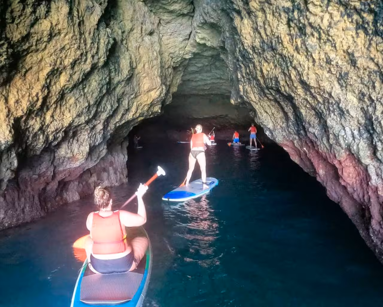 Adventurers kayaking through Benagil cave, experiencing unique Algarve coastline during 90-minute rental tour.