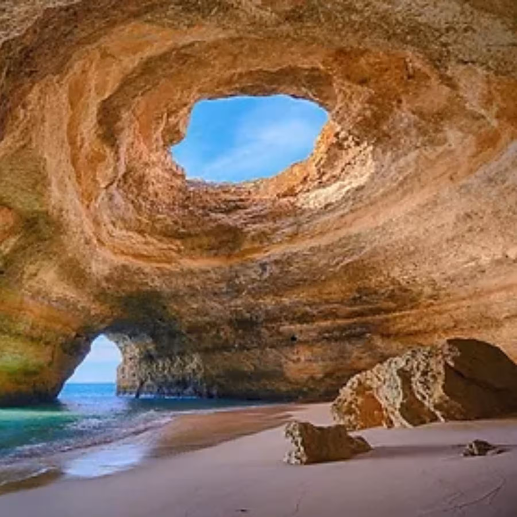 Stunning interior view of Benagil Cave in Algarve Portugal with natural skylight and sandy beach on guided kayak tour