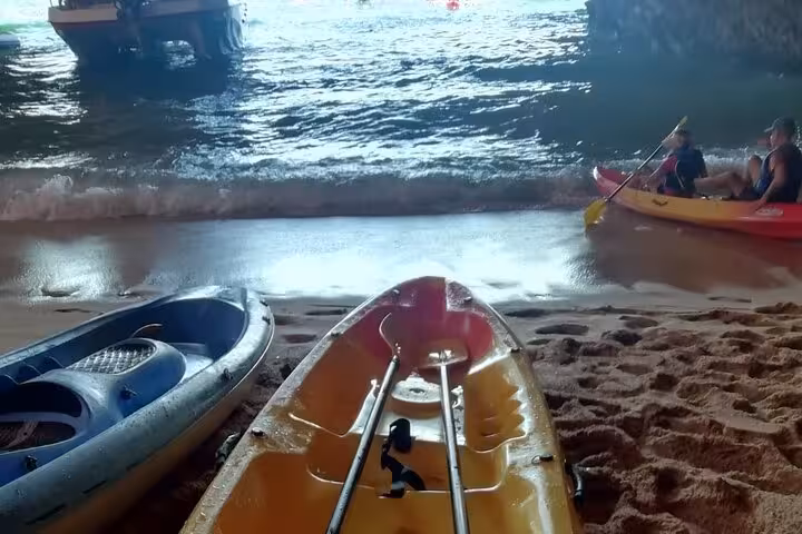 Kayaks on sandy shore inside a sea cave, launching for a guided Benagil sea caves kayak tour in Algarve