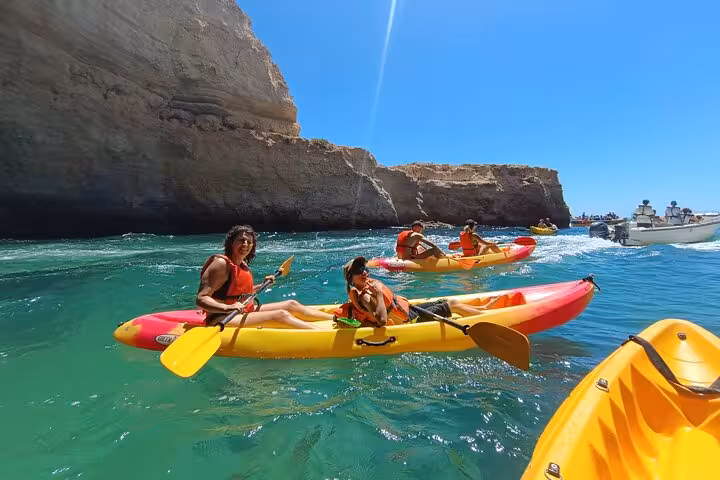 Kayakers in turquoise water near Benagil Cave cliffs, Algarve, on a guided sea caves kayak tour
