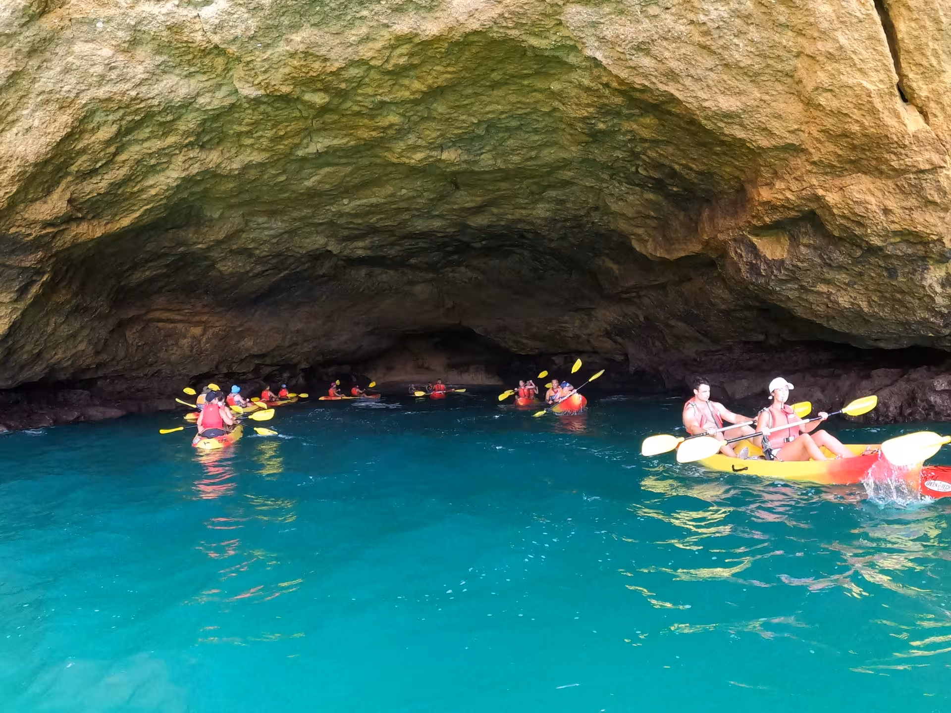 Small groups kayaking inside Benagil sea cave on turquoise water during guided Algarve coast catamaran and kayak tour