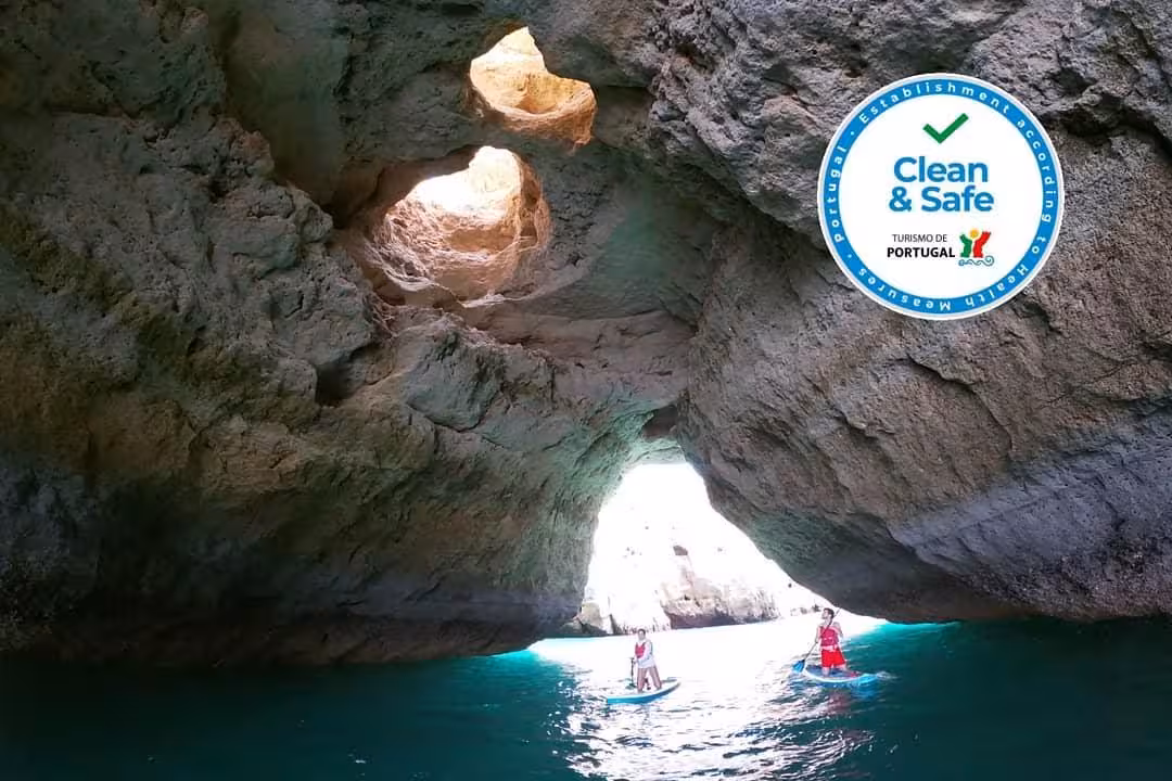 Paddleboarders glide through turquoise water inside Benagil Cave, Algarve, Portugal, on a certified clean and safe tour