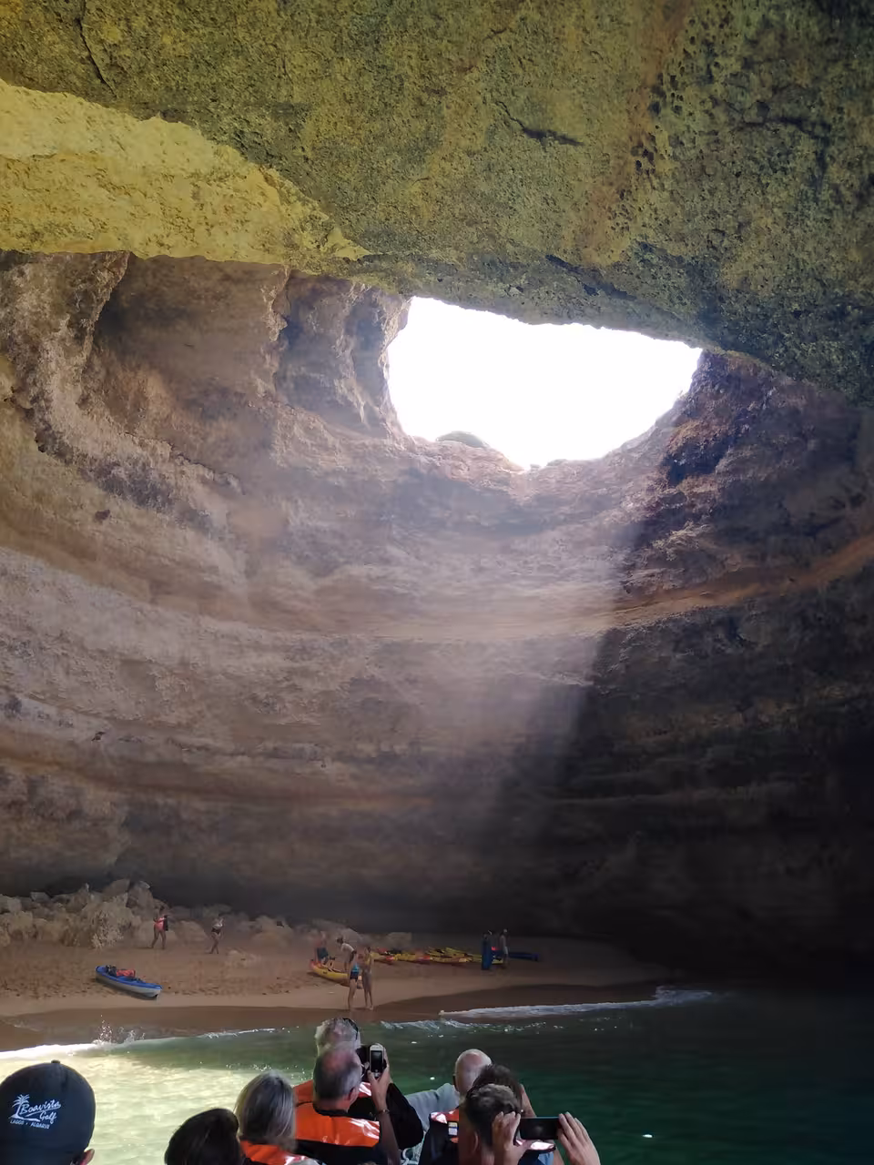 Tourists inside Benagil Cave from a private boat tour from Lagos Algarve with sunlight streaming through the iconic ceiling opening