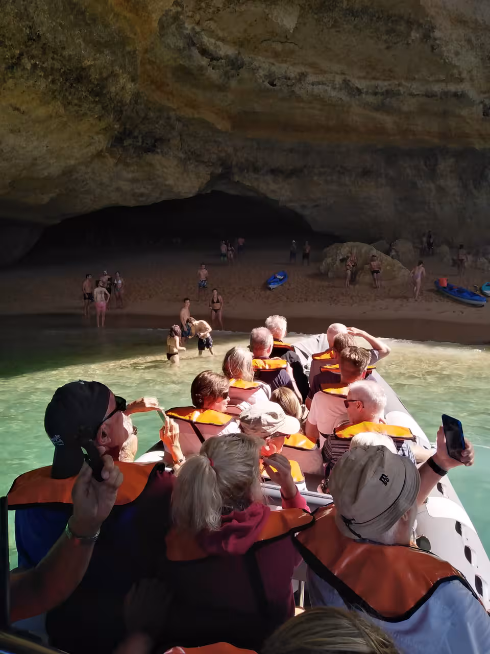 Excited tourists in life jackets photographing Benagil Cave interior on a private boat tour from Lagos Algarve Portugal