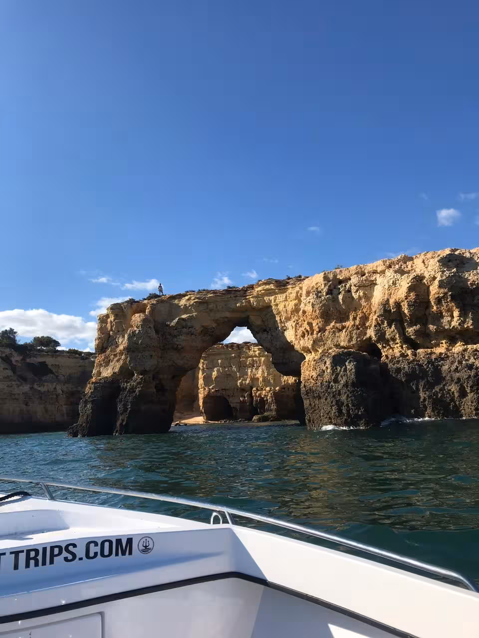 Private deluxe boat tour passing scenic Algarve natural rock arch along the stunning golden cliffside coastline of Benagil Portugal