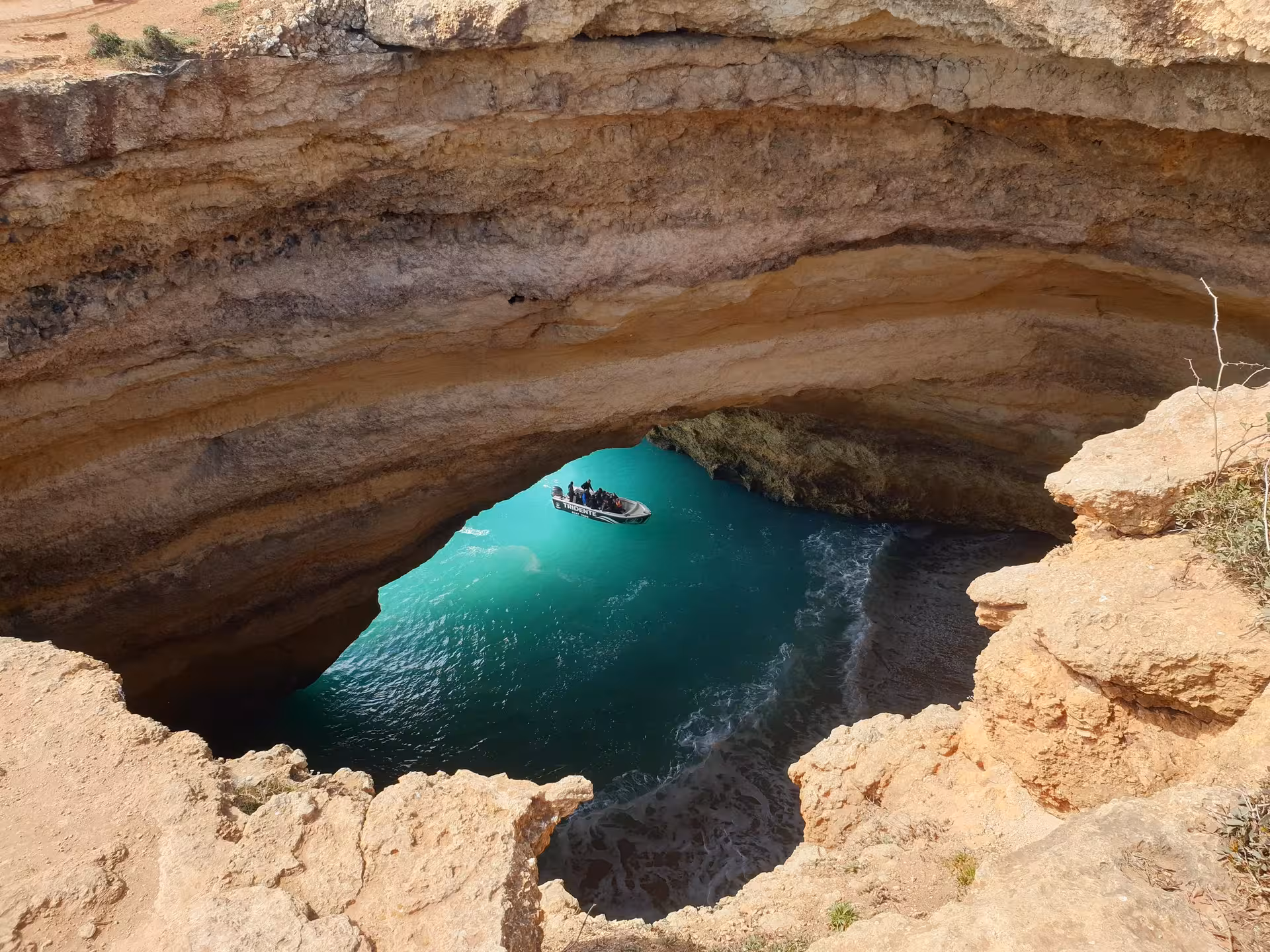 Aerial view of iconic Benagil Cave with turquoise waters and private deluxe tour boat navigating through the breathtaking sea cave opening