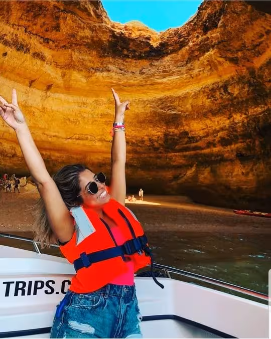Excited tourist in red life jacket posing joyfully inside the stunning Benagil Cave on a private deluxe boat tour