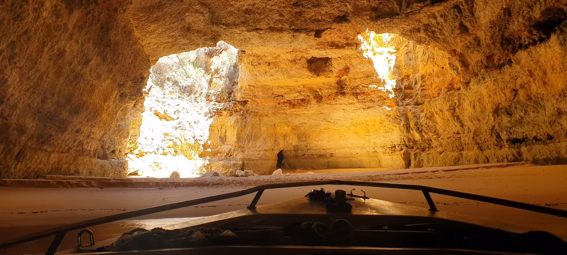 Inside view of Benagil Cave from a private boat revealing glowing golden rock walls and natural skylights on a deluxe sea cave tour in Algarve Portugal.