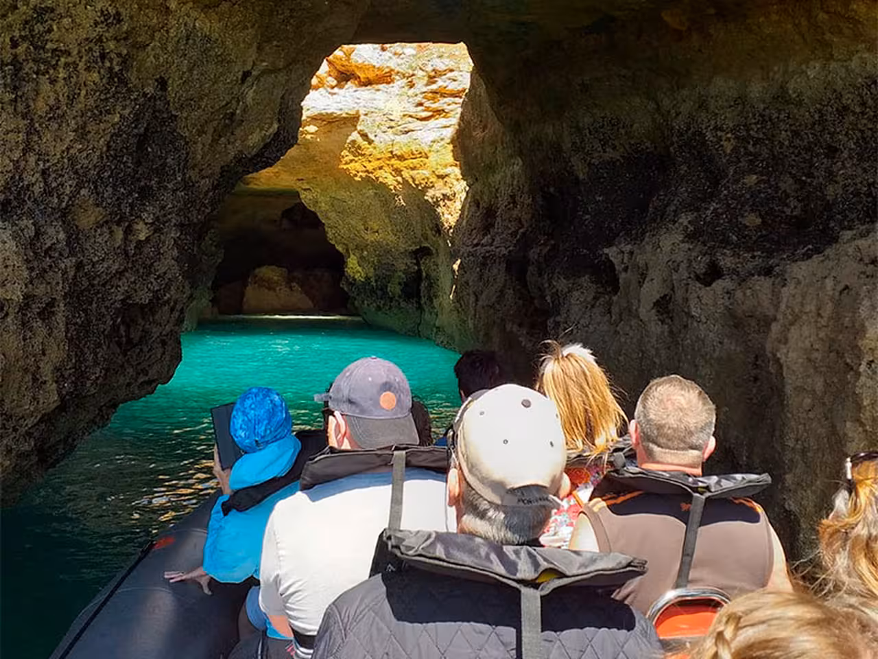 RIB boat passengers entering Benagil Cave on Albufeira dolphin watching tour, turquoise water and sea arch