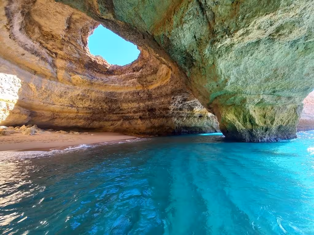 Crystal-clear turquoise water and golden sand inside Portugal’s Benagil Cave, visited on a scenic Algarve boat tour