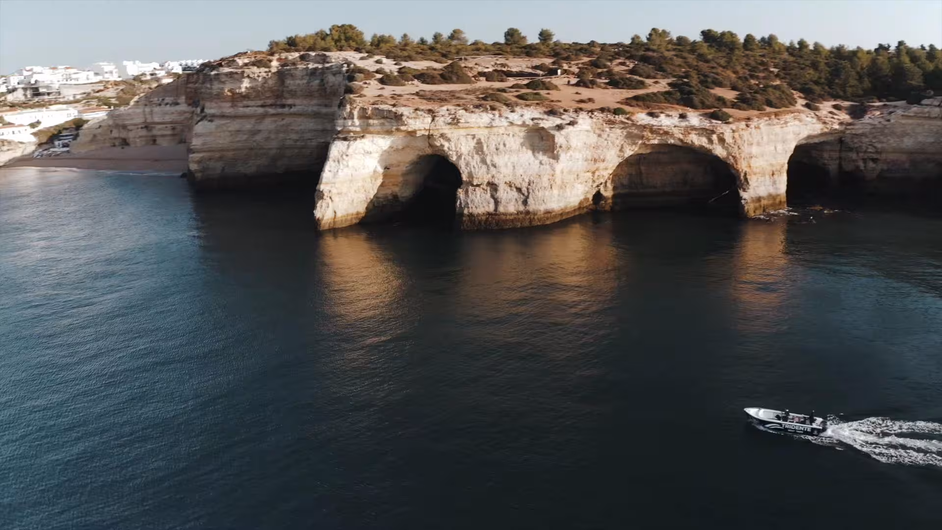 Aerial view of stunning Benagil Cave limestone cliffs with a tour boat cruising the Algarve coastline Portugal