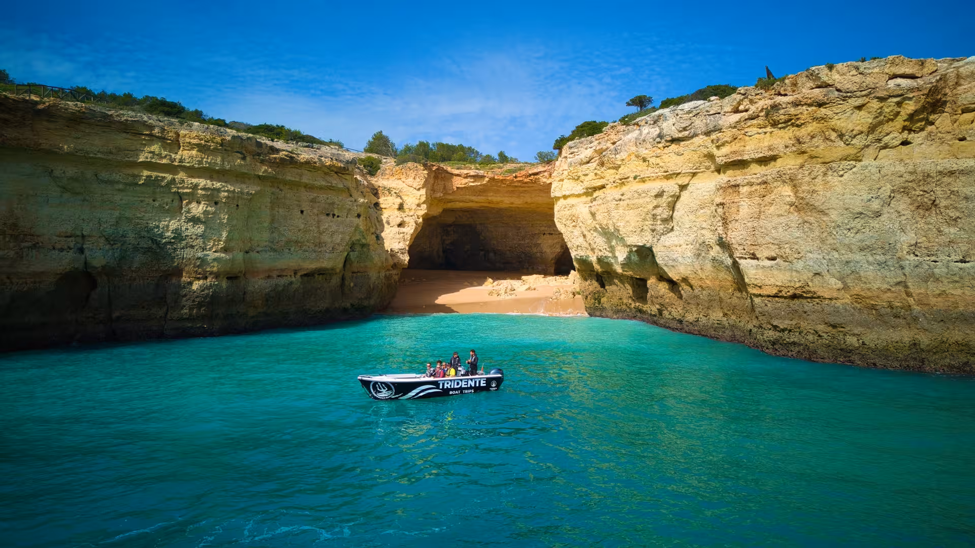 Small Tridente boat entering the turquoise waters of Benagil Cave on a guided Algarve sea caves tour from Carvoeiro