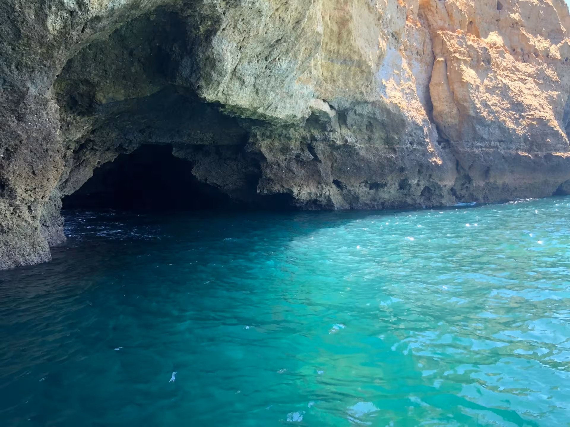 Crystal-clear turquoise waters leading into a mysterious cave at Algarve's coastline, perfect for exploration tours.