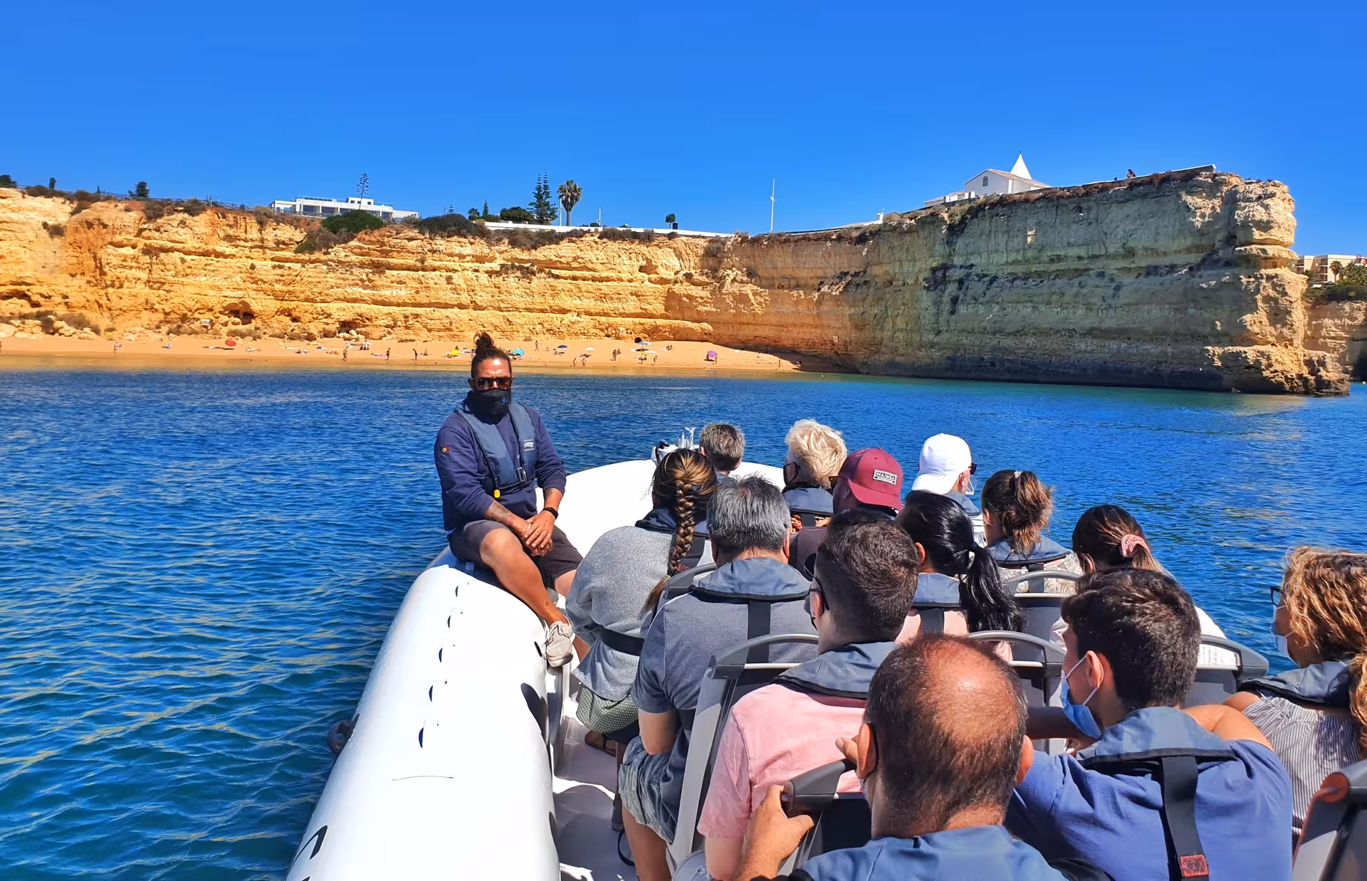 Tourists enjoy a boat tour along the stunning Algarve coast near Benagil Caves, with golden cliffs and clear blue waters.
