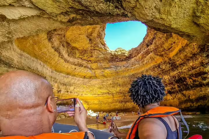 Visitors enjoy a boat tour inside the stunning Benagil caves during a private Milfontes to Algarve trip, capturing scenic views.