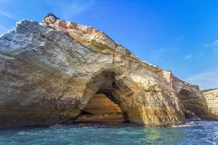 Stunning view of the Benagil caves from a boat tour on the Milfontes to Algarve private excursion, under a clear blue sky.