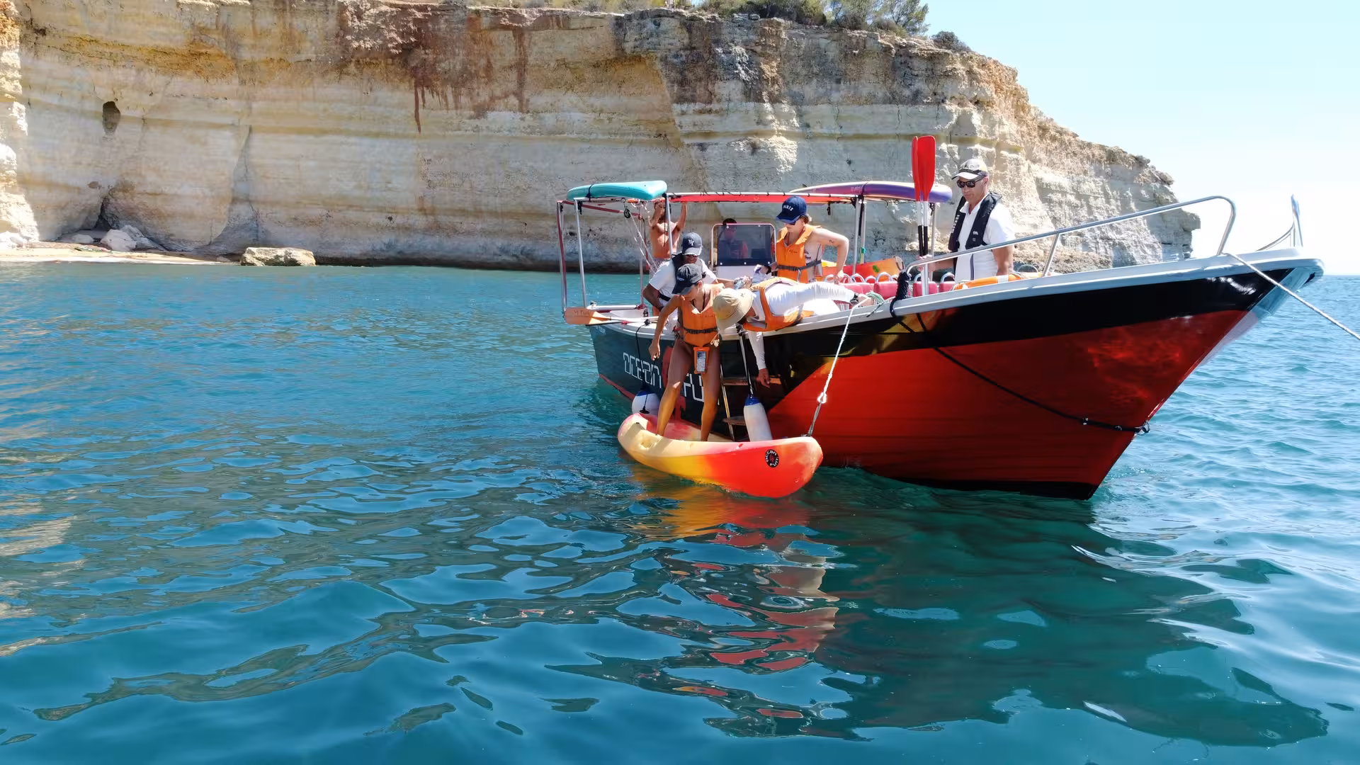Tour boat with guests anchored near golden limestone cliffs on a 2.5-hour Benagil Caves boat tour Portimao