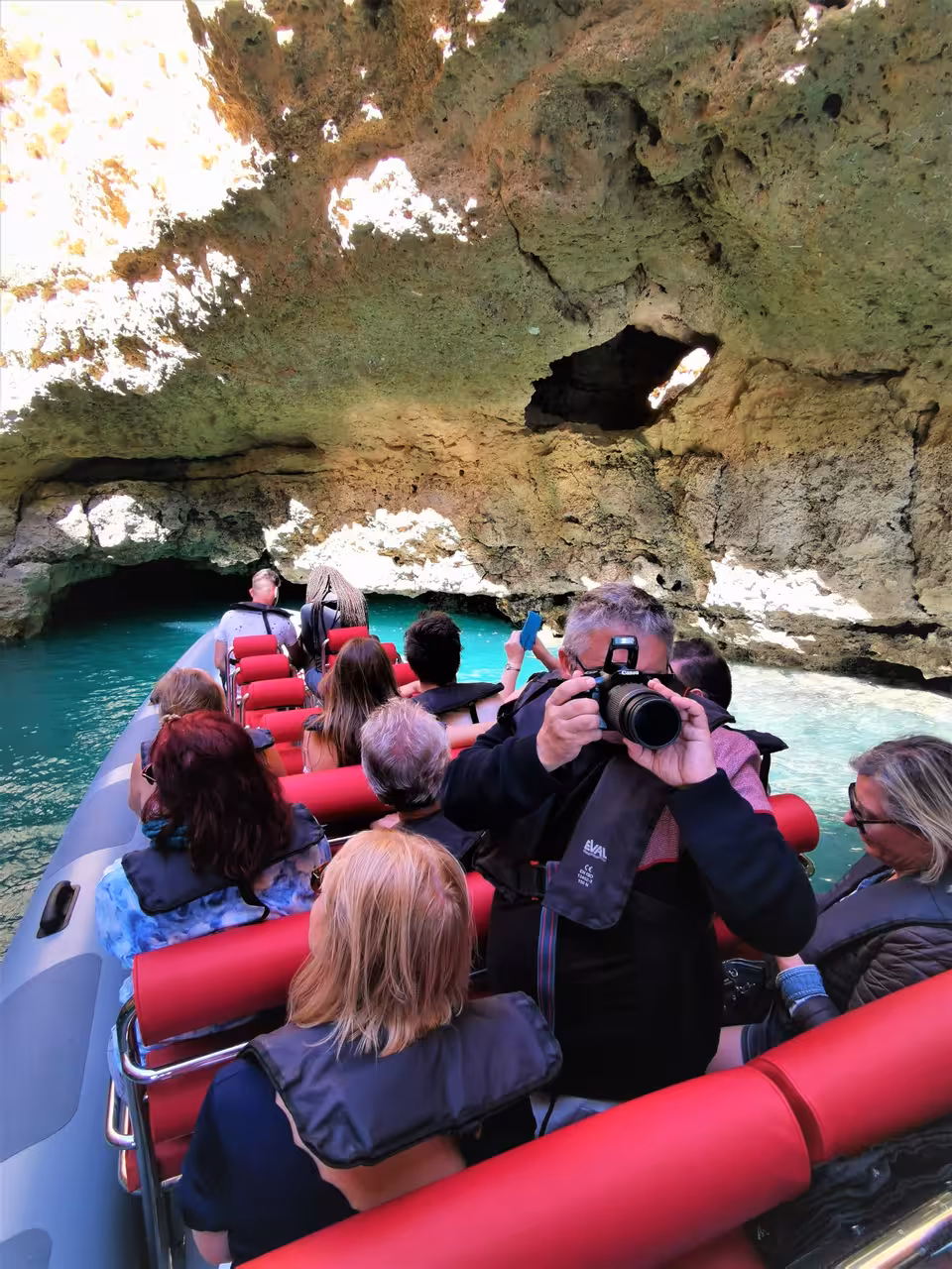Passengers on Albufeira Marina boat tour exploring Benagil sea cave, Algarve, with turquoise water views