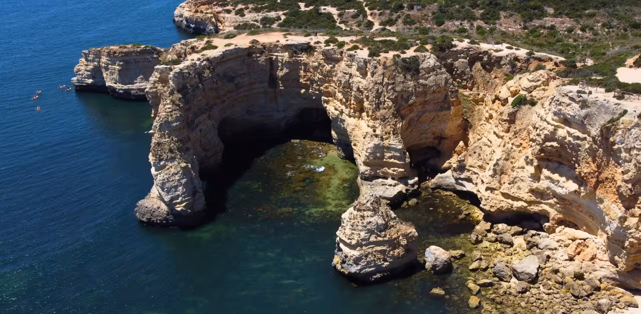 Kayakers explore the dramatic limestone cliffs and secluded sea caves along the Benagil coastline in the Algarve