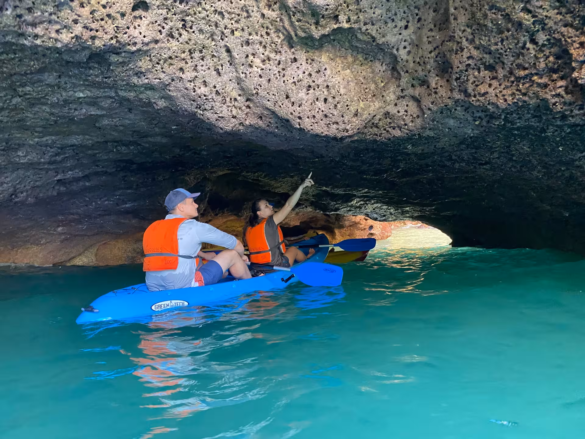 Couple on Benagil Caves kayak experience gliding through turquoise water beneath low Algarve sea cave ceiling in southern Portugal