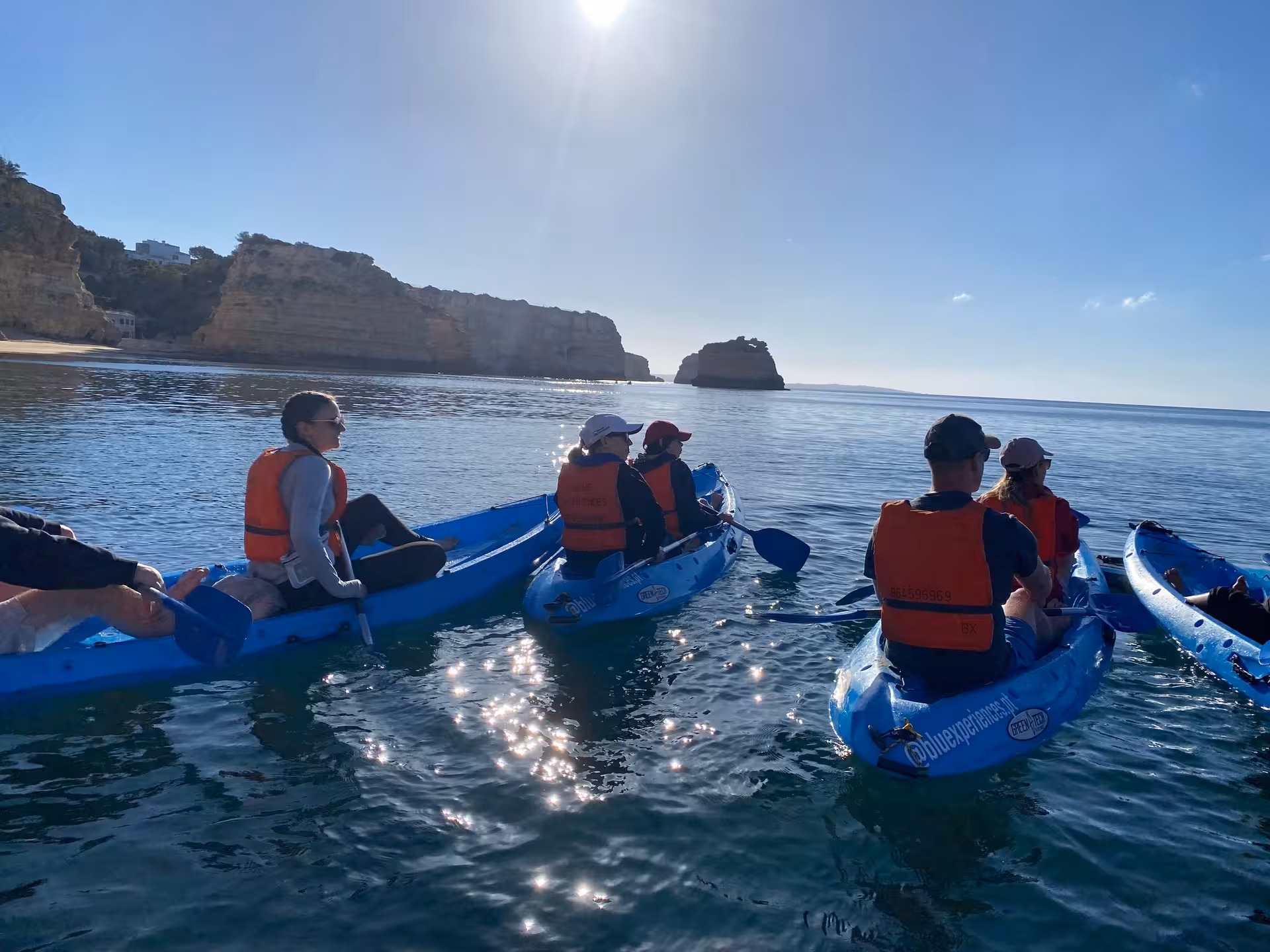 Guided Benagil Caves kayak tour group paddling along the Algarve coast with golden cliffs and calm Atlantic Ocean views