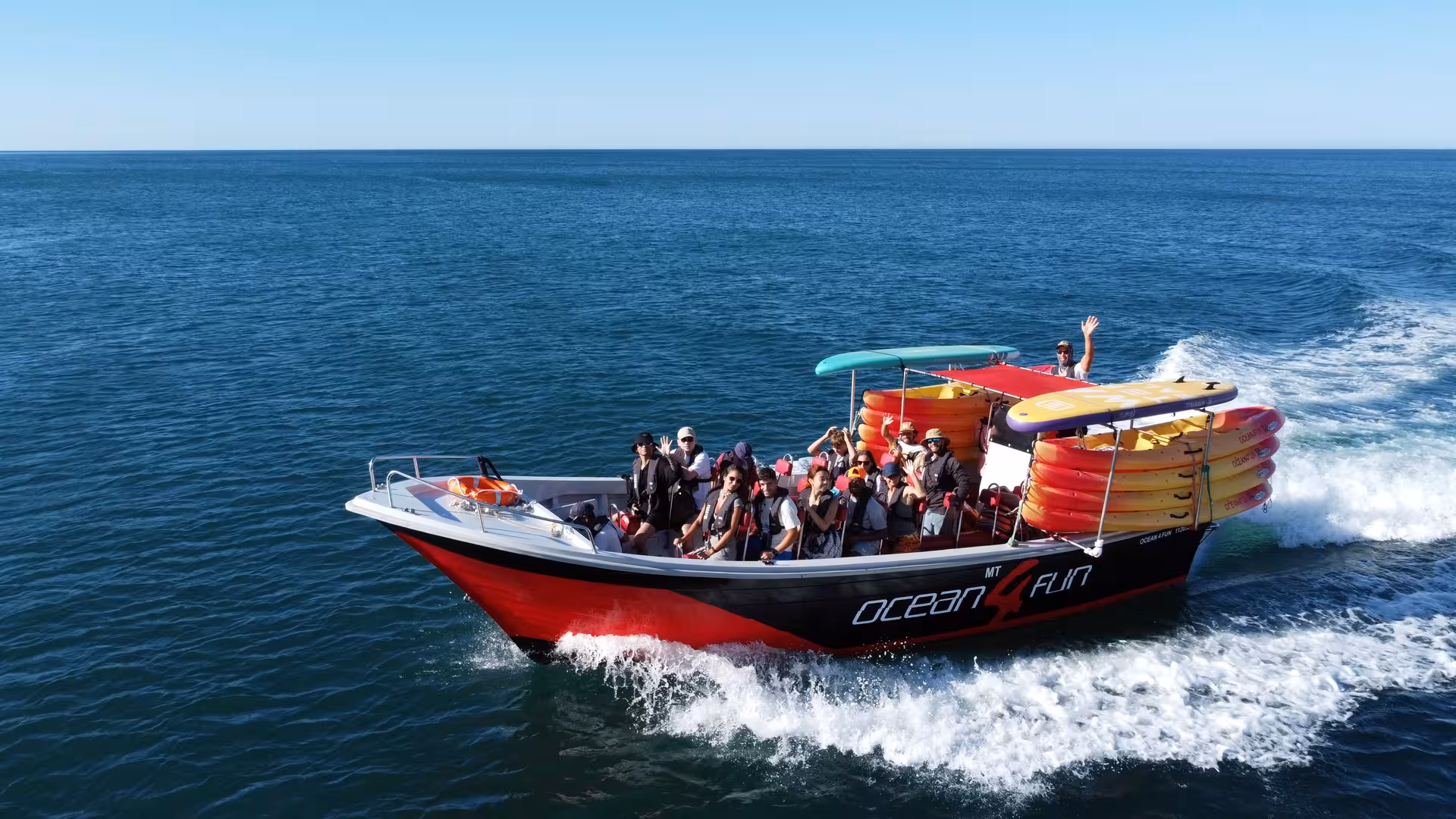 Excited tourists aboard Ocean 4 Fun speedboat cruising the Atlantic on a 2.5-hour Benagil Caves tour from Portimao