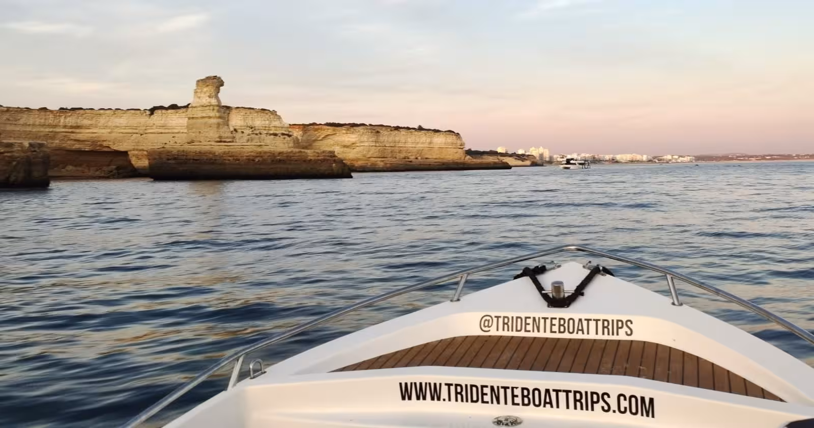 Bow of Tridente boat on private Benagil Caves sunset cruise, approaching Algarve limestone cliffs near Portimão coastline
