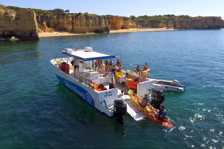 Support boat launching kayaks for Benagil Kayak Tour along Algarve cliffs and calm ocean near sandy beach