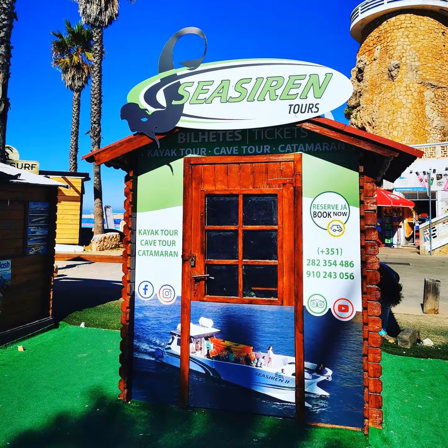 Seasiren Tours wooden ticket booth on Benagil beach promoting Algarve kayak and cave tours with contact details