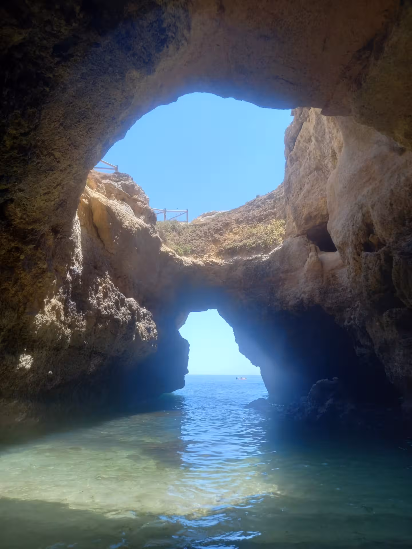 View from inside an Algarve sea cave toward the ocean arch and blue sky, scenic Benagil kayak rental route