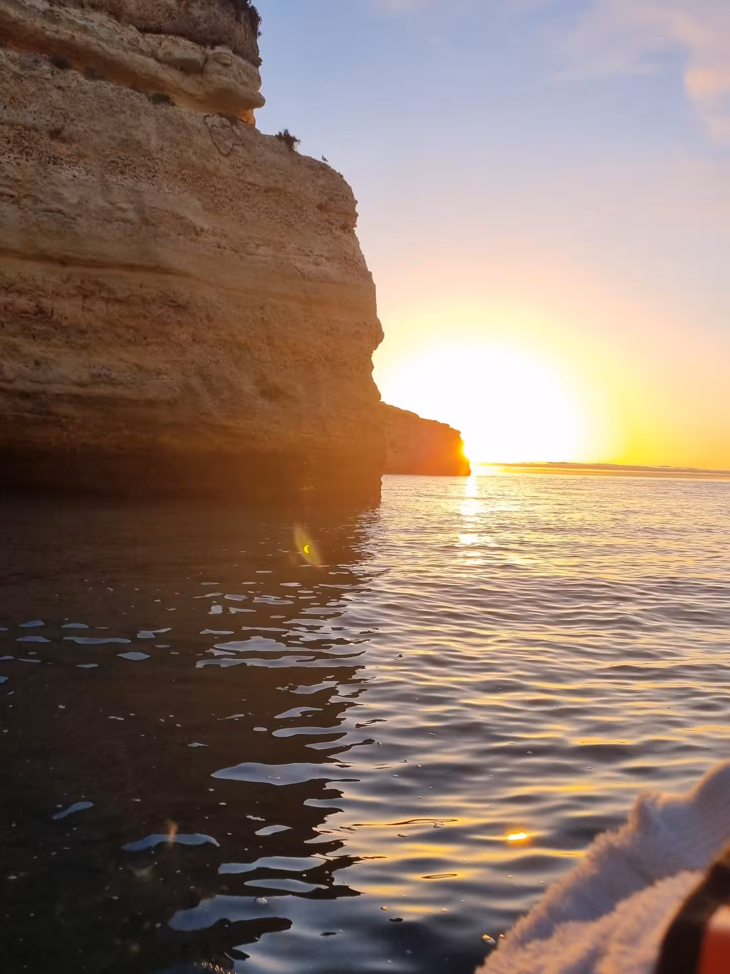 Golden sunrise glowing behind Benagil sea cliffs on an Algarve boat cave tour at dawn