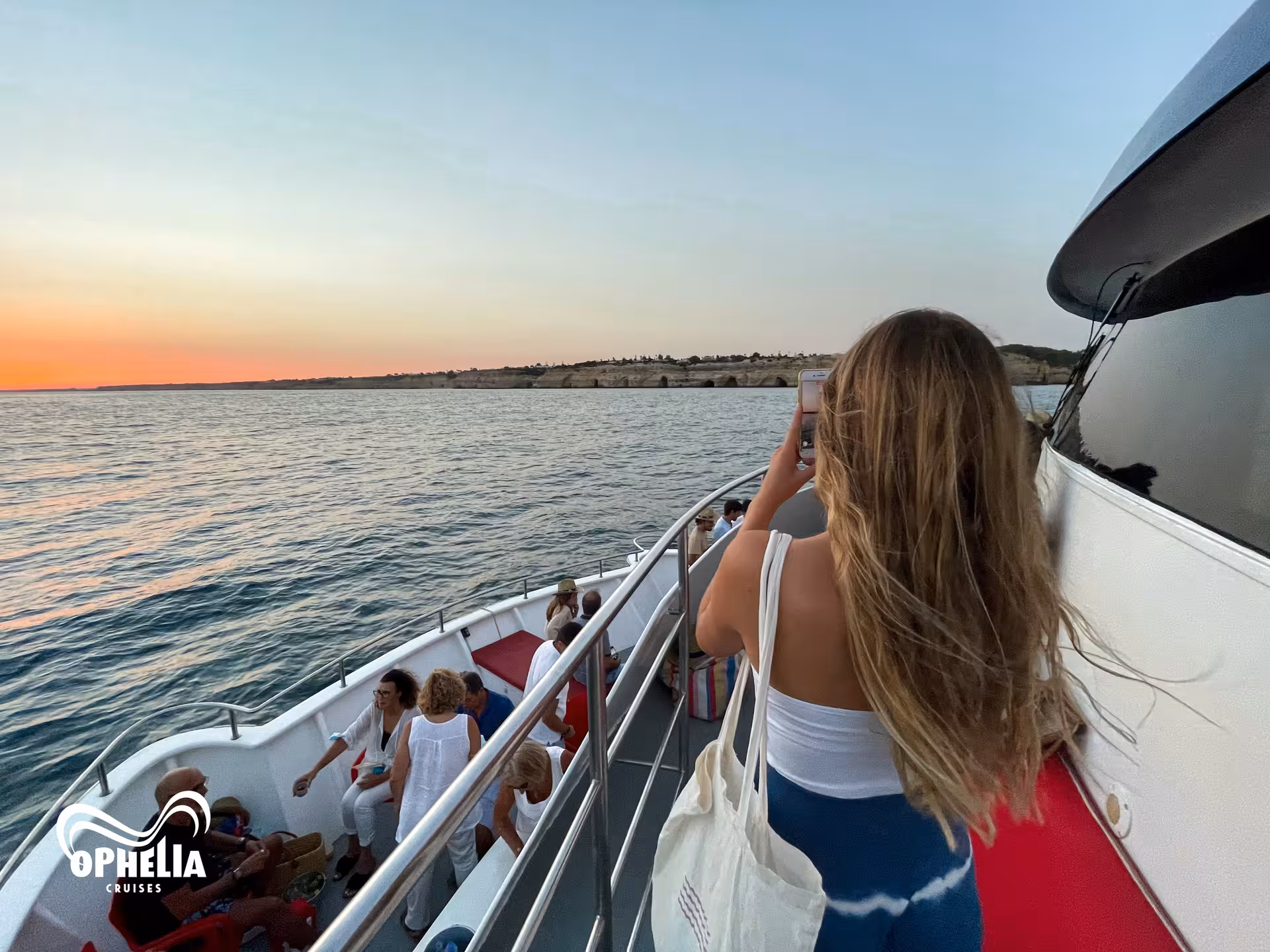Tourist photographing the serene ocean view during the Benagil Sunset Ophelia cruise along the Algarve coast.