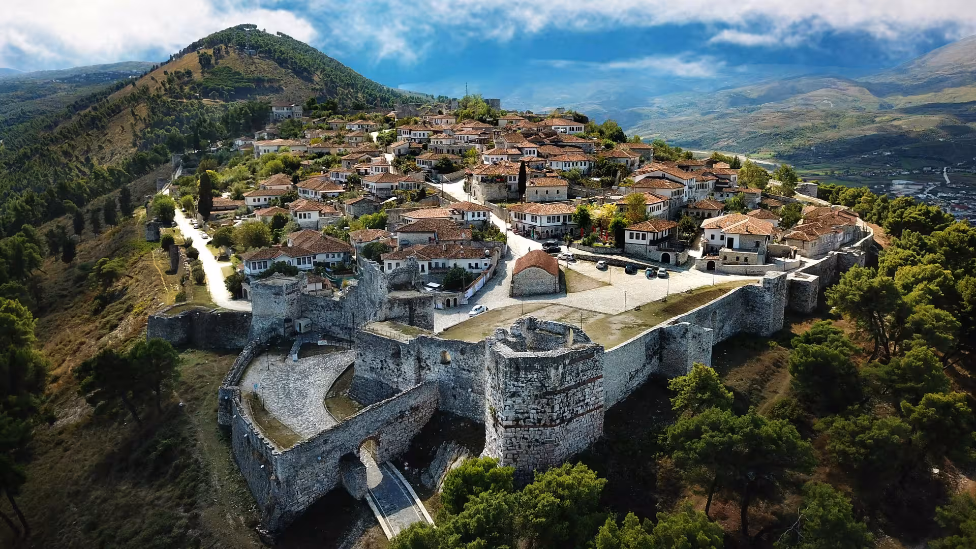 Aerial view of Berat Castle, Albania, showcasing historic stone structures amid scenic mountainous landscape.