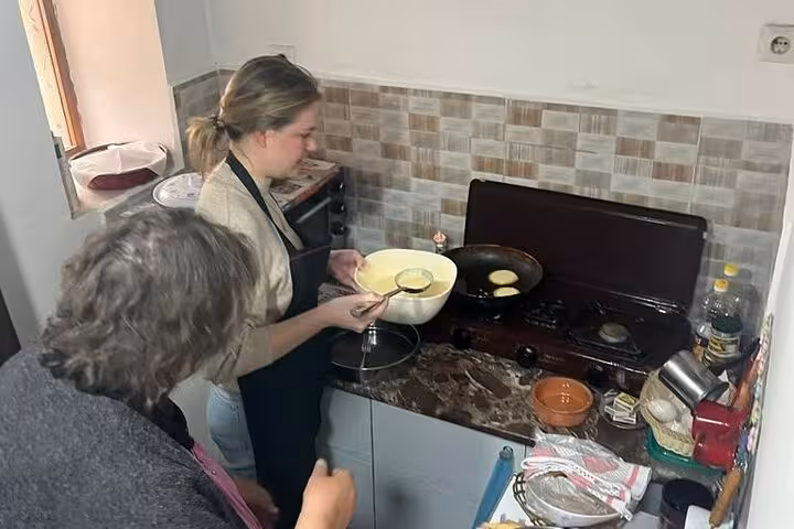 Guests pour batter to make traditional Albanian pancakes in an engaging Berat cooking class experience.
