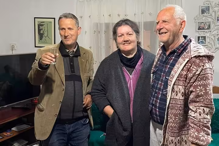 Three people smiling and enjoying traditional Albanian hospitality during the Berat Cooking Class experience.