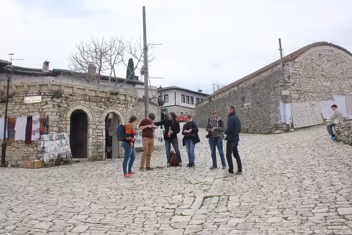 Group of tourists exploring the cobbled streets of Berat with expert guides, surrounded by historic stone architecture.