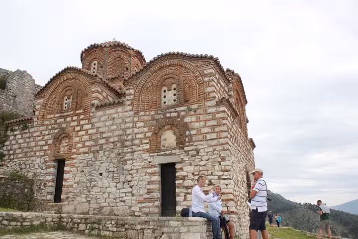 Visitors exploring the historic architecture of Berat, featuring ancient stone buildings on a guided walking tour.