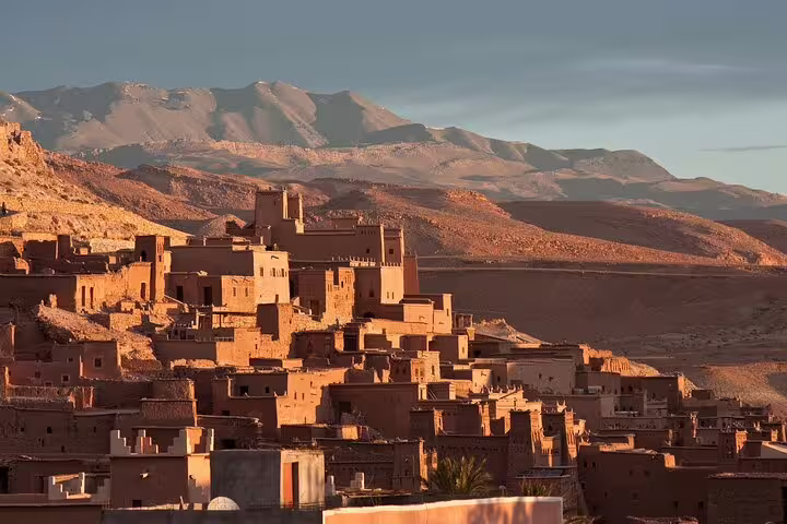 Traditional Berber kasbah at sunset with rugged Atlas Mountains backdrop, stop on Marrakech to Ourika Valley tour