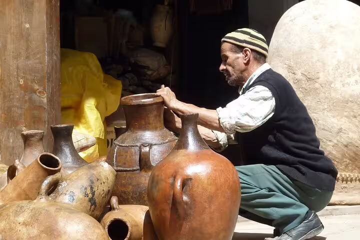 Berber pottery artisan crafting clay jugs on 3-day Marrakech to Sahara tour, authentic Morocco culture