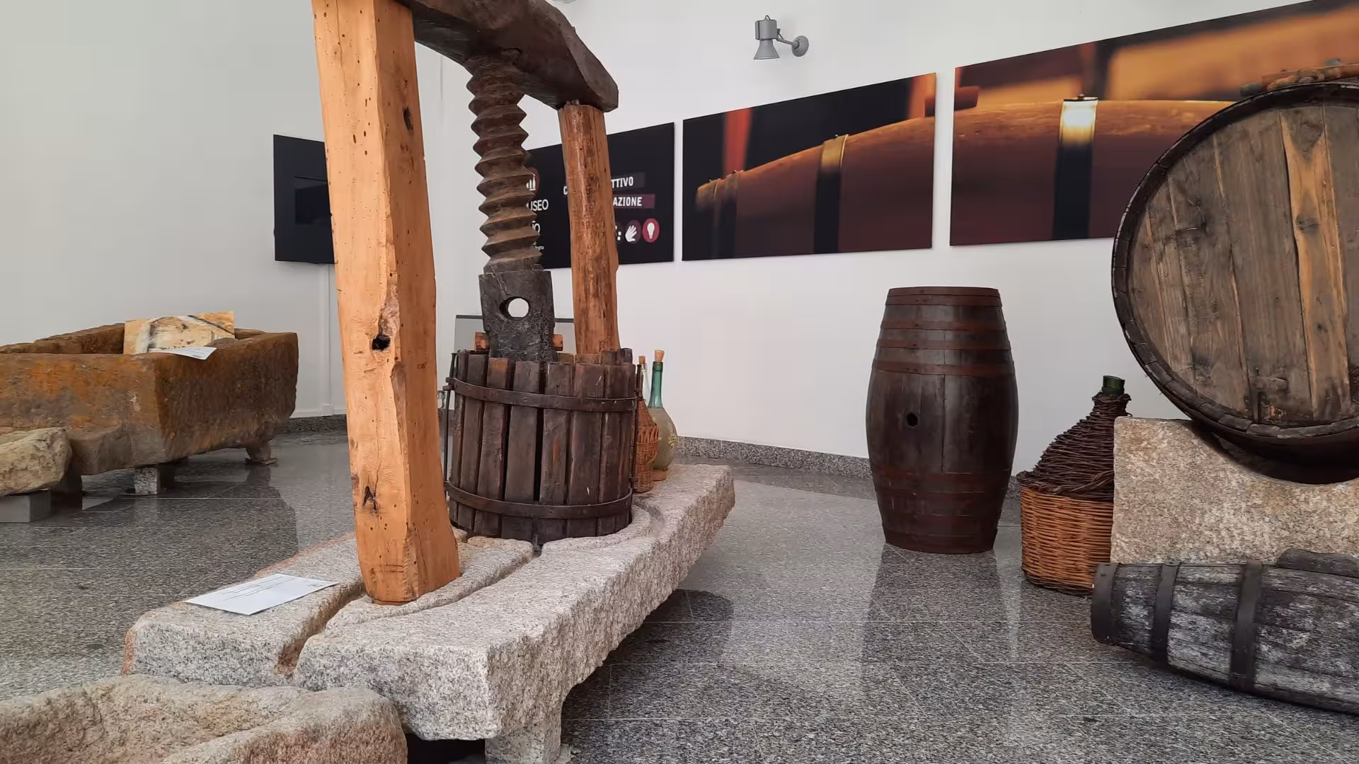 Traditional wine press and barrels exhibited at Berchidda Wine Museum, offering insights into historical winemaking.