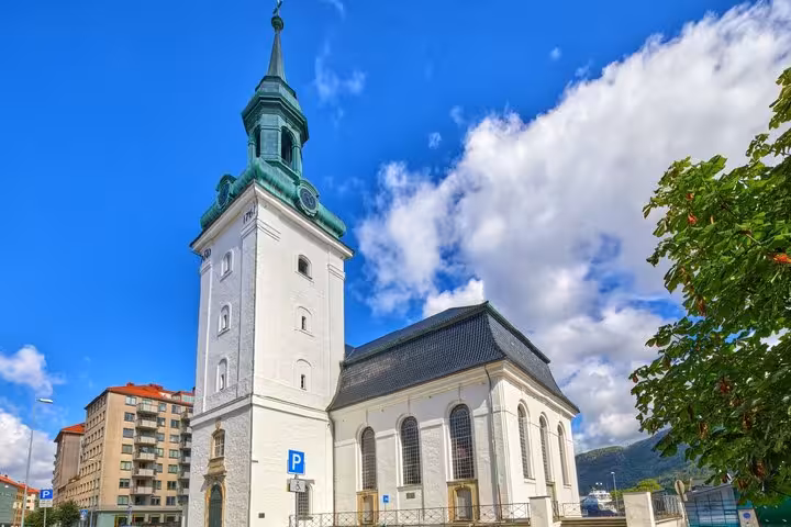 White church with green copper spire tower in Bergen city center on a sunny day