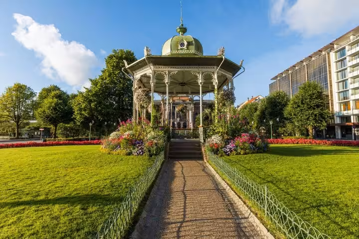 Historic Victorian bandstand with green dome surrounded by colorful flowers in Bergen city park