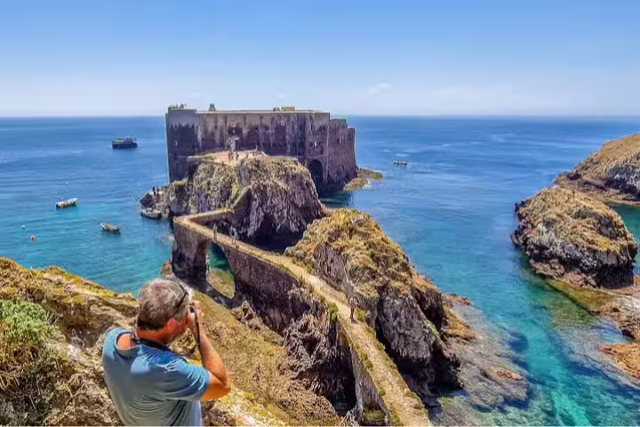 Traveler photographs the stunning São João Baptista Fort on Berlengas Island, showcasing clear blue waters and rugged cliffs.